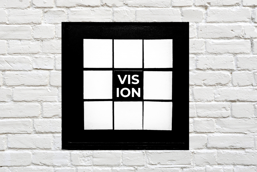 A black and white vision board displaying nine black squares, with 'VISION' at the centre.