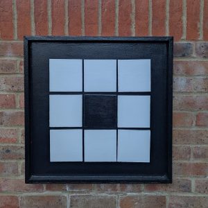 Black vision board with one black square in the centre of a white grid pattern.